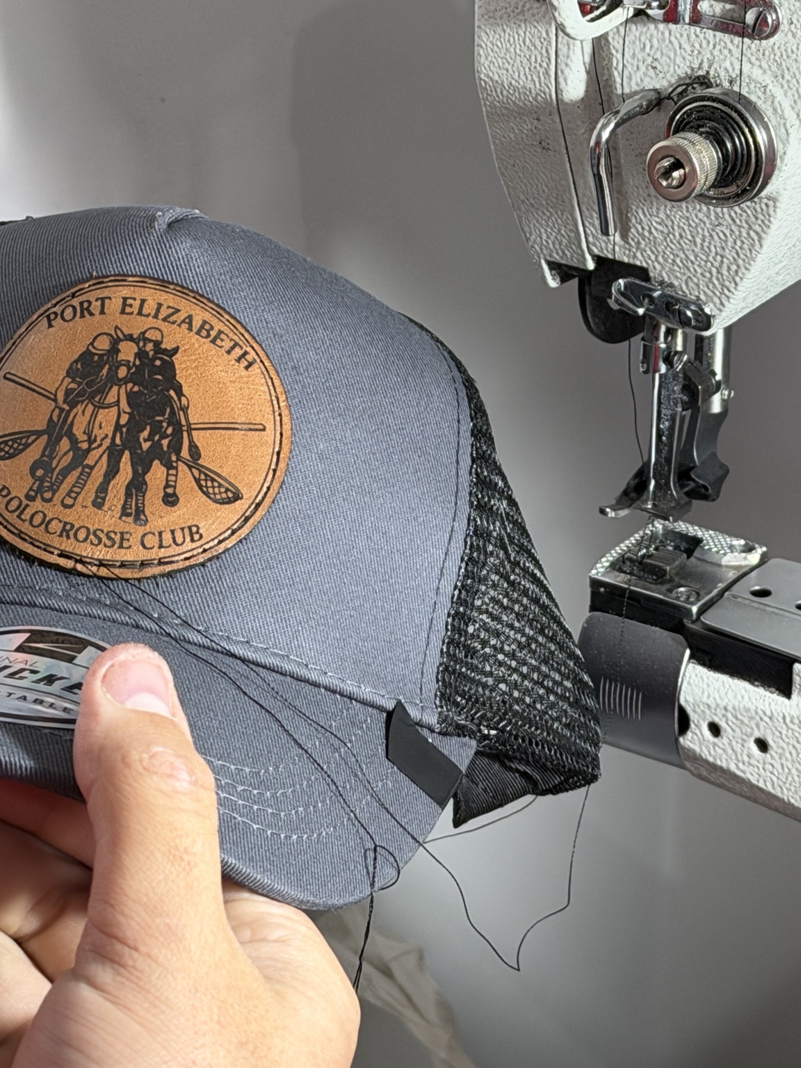 Leather patch being sewn onto cap